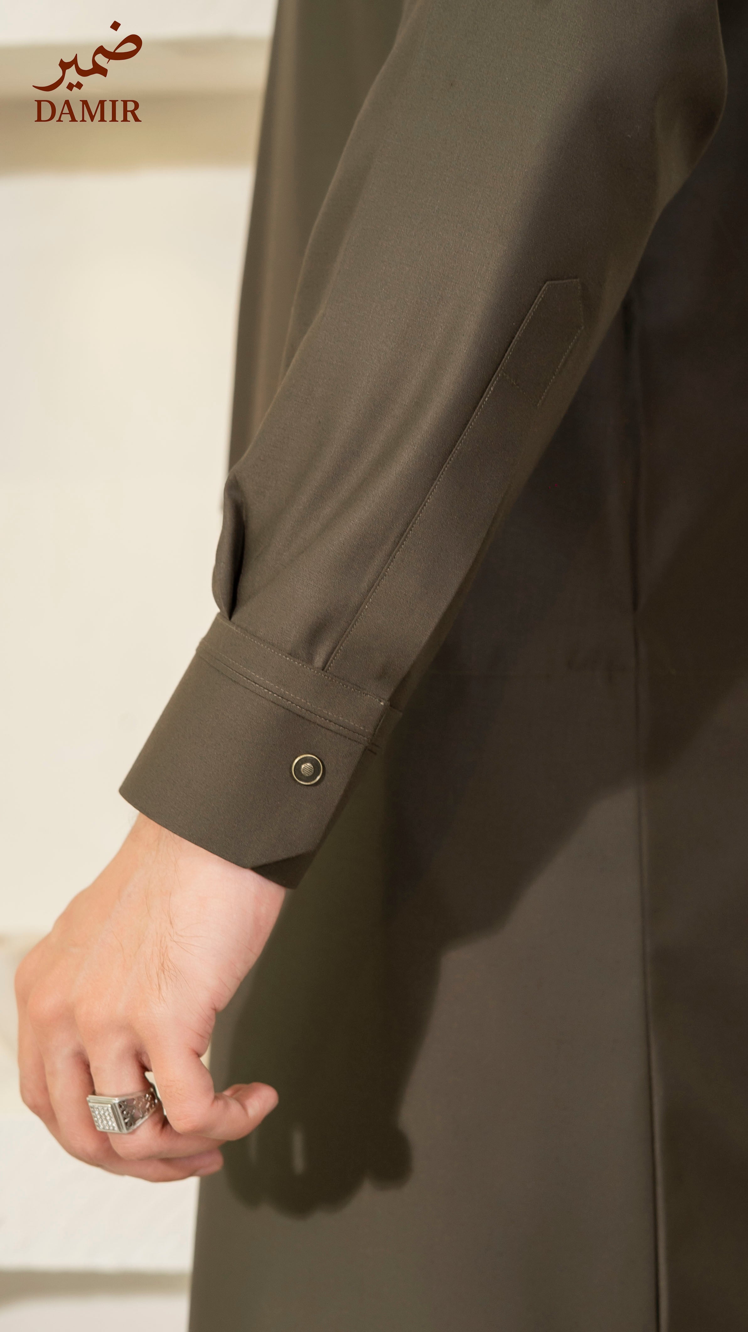 Brown long coat with a close-up of the sleeve and hand, featuring the brand 'DAMIR'.