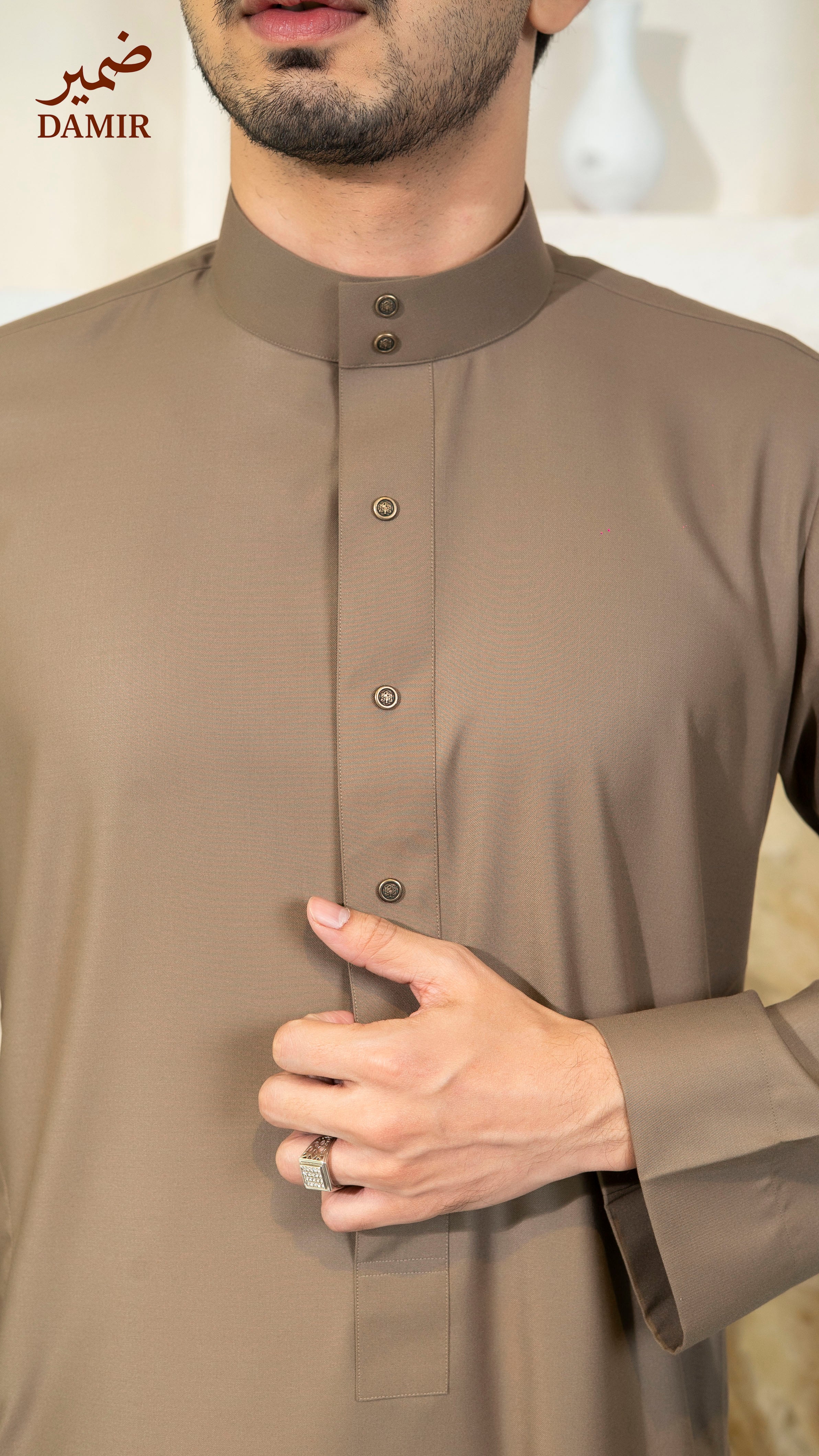 Man wearing a brown traditional outfit with 'DAMIR' branding.